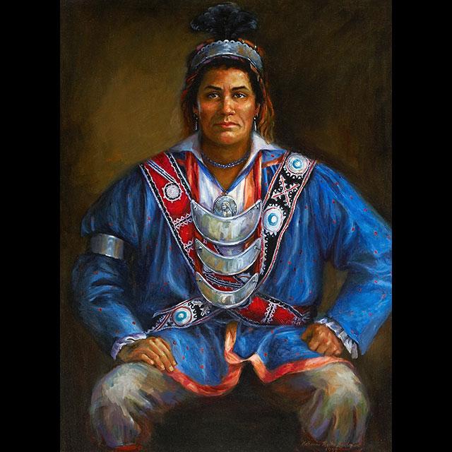 A color portrait of Pushmataha who is seated. The Choctaw Chief is painted facing forward with his hands resting on his thighs and is wearing a long-sleeved blue tunic trimmed in red and dark blue pants. Two sashes (one red and one dark brown) cross his upper body and three silver gorgets hang down from his neck. The shirt underneath is white and ruffled.