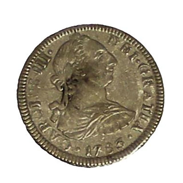 A silver coin from the El Cazador shipwreck. The coin was worth two reales. In the center is the profile of Carolus III facing right, surrounded by text that reads: “Carolus III De Gratia 1783.”