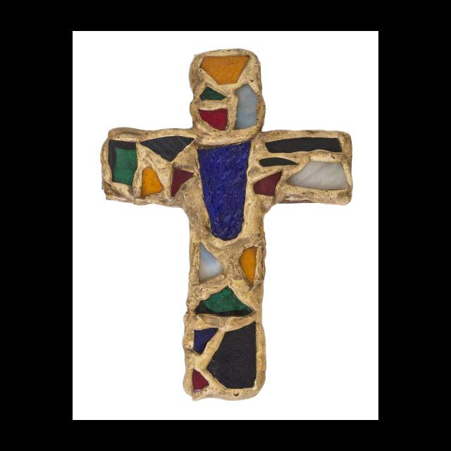 angular, and many shapes and sizes. They range in color, with orange, green, red, blue, black, and white pieces arranged over the surface. Tan grout fills in between the glass pieces and forms the rectangular outline of the cross.